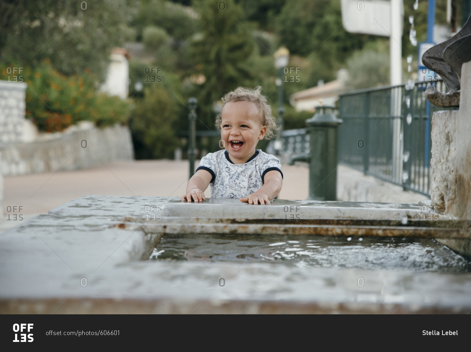 Happy young boy playing at a fountain