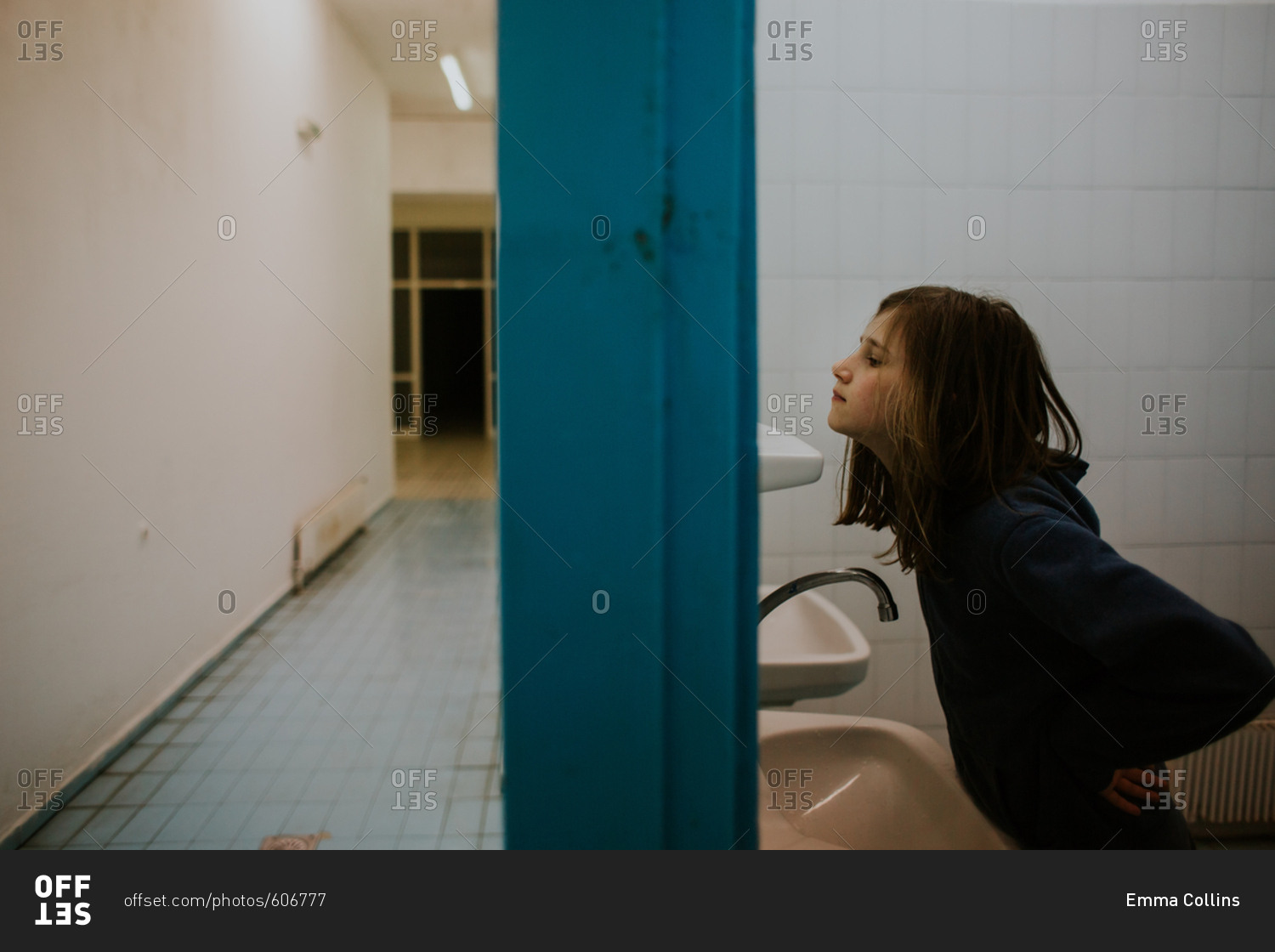 Pre-teen girl looking in bathroom mirror stock photo - OFFSET