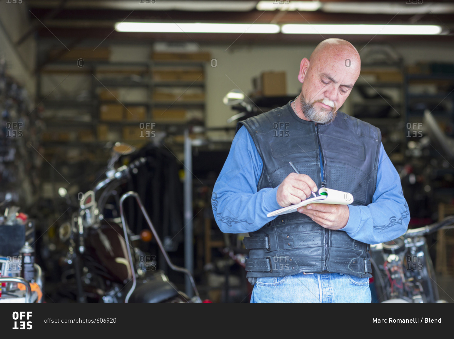 Caucasian man near motorcycle writing on notepad