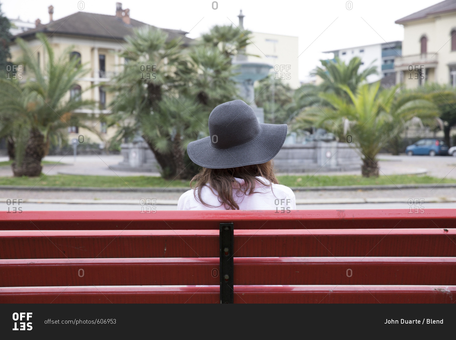 Woman wearing sun hat sitting on red bench