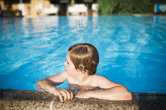 Boy hanging on the edge of a swimming pool