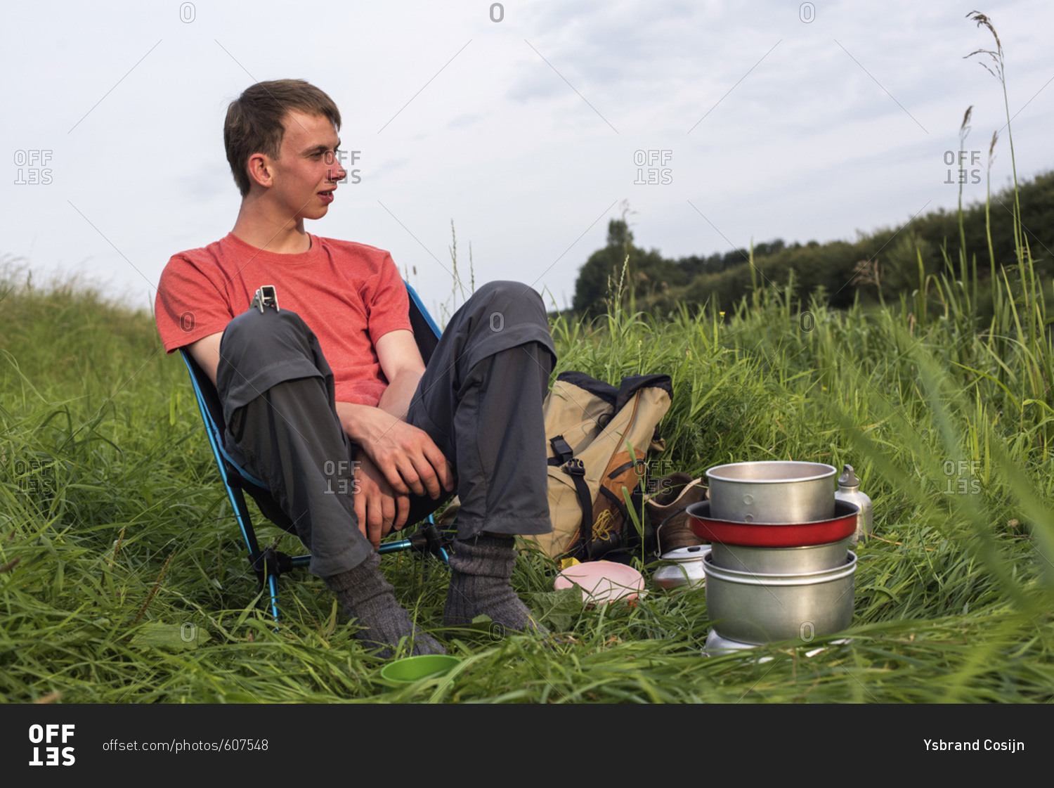 Teen man sitting in chair with camping stove enjoying nature