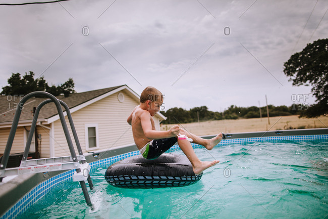A boy jumping onto a pool inflatable pool toy