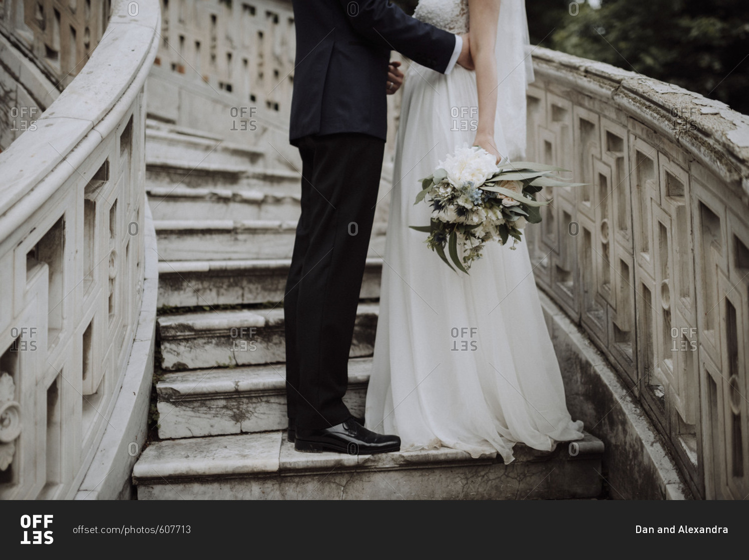 Groom standing on staircase next to bride holding wedding bouquet