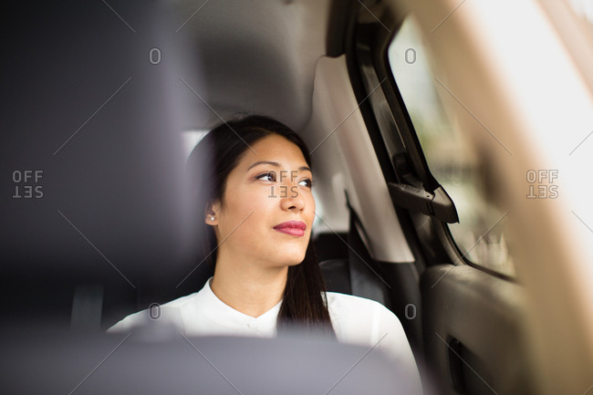 Businesswoman looking out of window of taxi cab