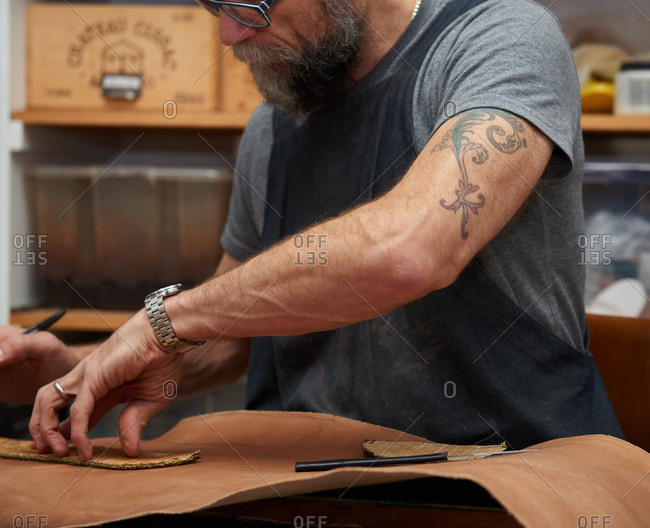 London, England - December 15, 2015: Shoemaker cutting pattern pieces from leather