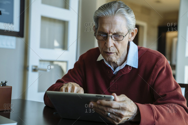 Senior man using tablet computer in financial advisor's office