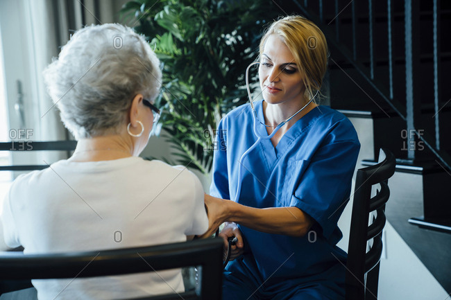 Caregiver checking blood Pressure of senior woman at home