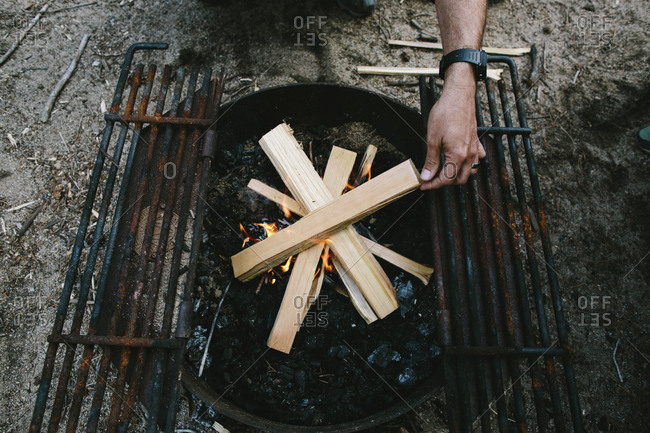 High Angle View Of Man Burning Firewood In Fire Pit At Campsite