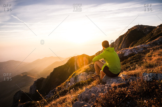 Man on mountain top watching sun