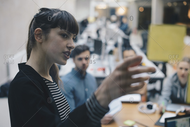 Computer programmer explaining adhesive note to colleagues in office