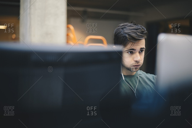 Male computer programmer puffing cheeks while using desktop PC in office