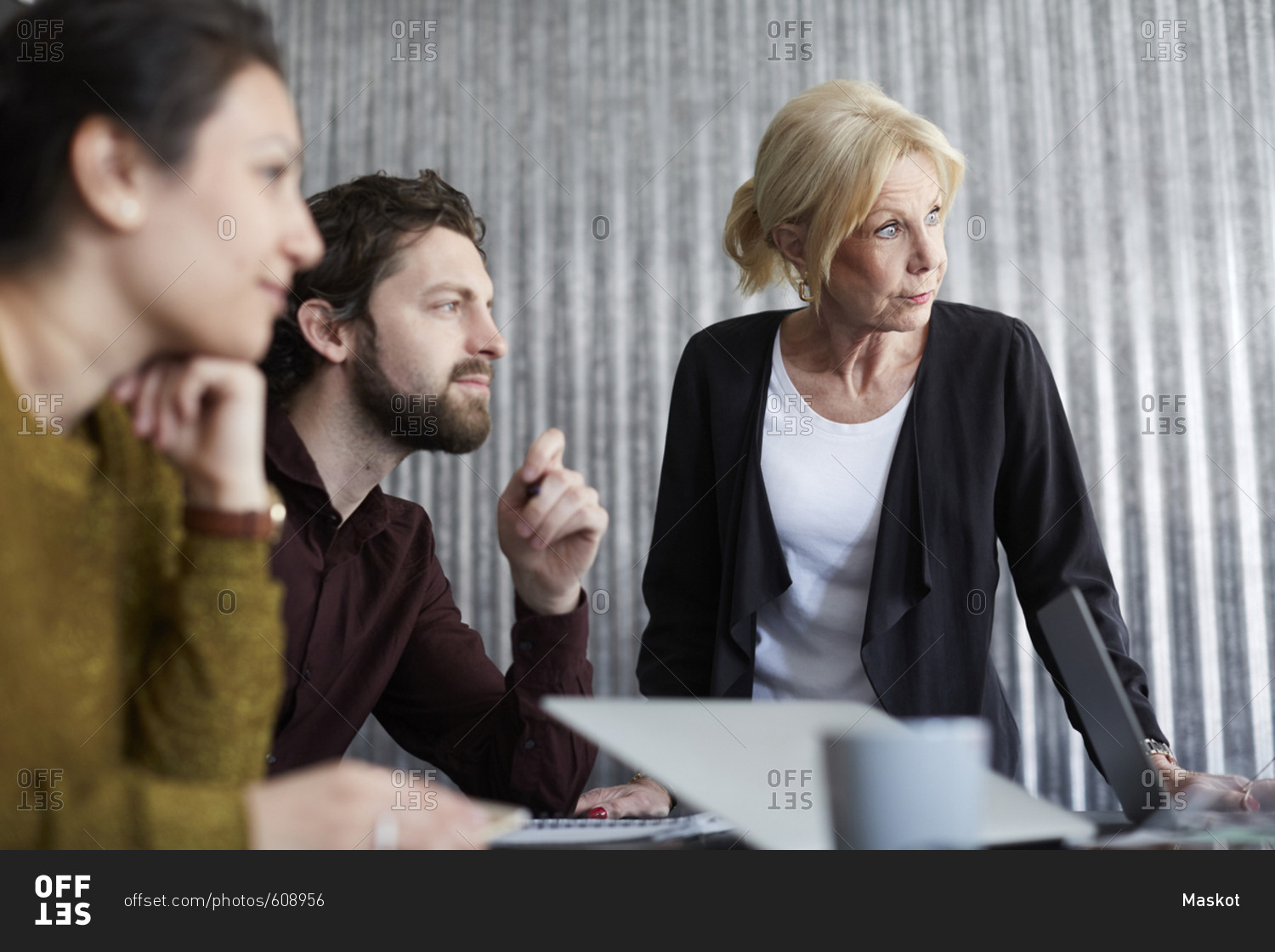 Senior businesswoman with mid adult colleagues looking away in board room