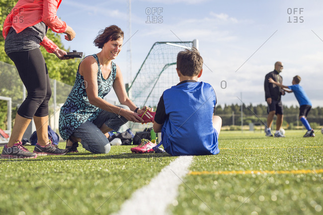 Mothers helping sons (10-11, 12-13) get dressed for soccer practice