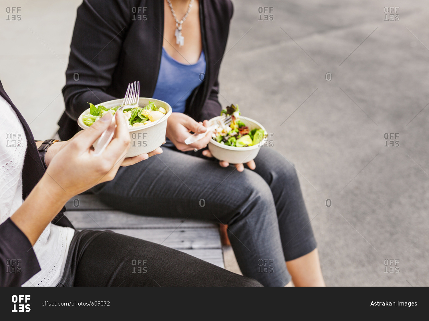 Mid section of two women eating salad