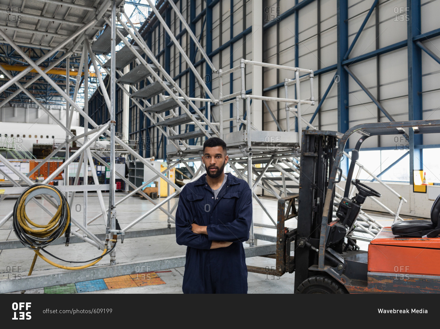 Portrait of aircraft maintenance engineer standing with arms crossed at airlines maintenance facility