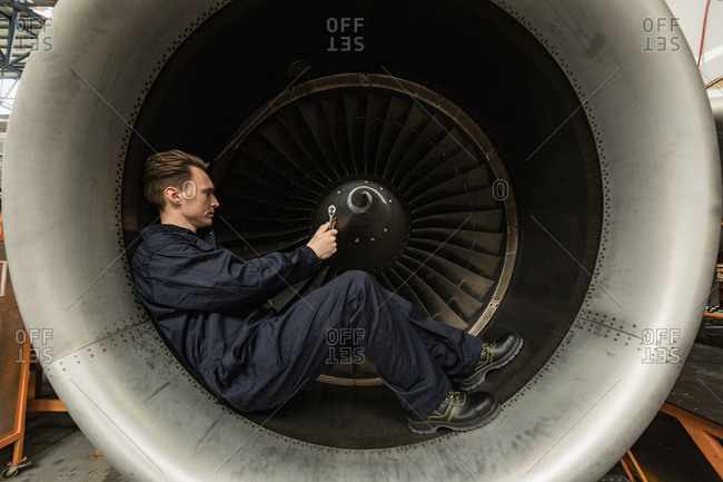 Male aircraft maintenance engineer fixing turbine blade of aircraft at airlines maintenance facility