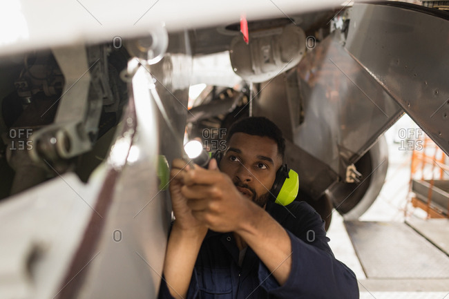 Male aircraft maintenance engineers working over an aircraft at airlines maintenance facility