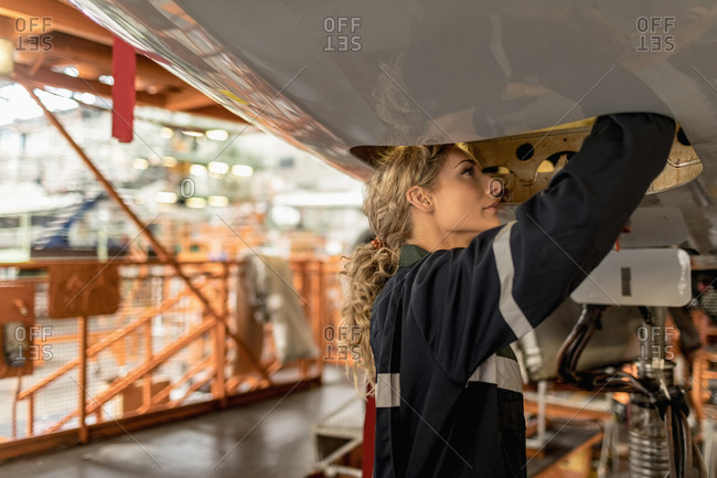 Female aircraft maintenance engineers working over an aircraft engine at airlines maintenance facility