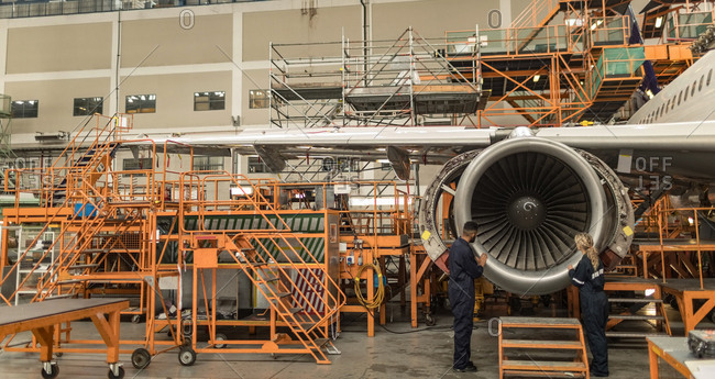 Aircraft maintenance engineers examining turbine engine of aircraft at airlines maintenance facility