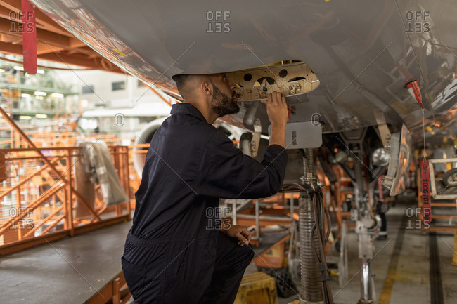 Male aircraft maintenance engineers working over an aircraft engine at airlines maintenance facility