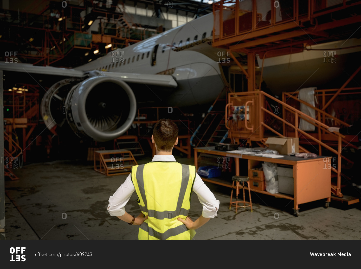 Rear view of female aircraft maintenance engineer standing at airlines maintenance facility