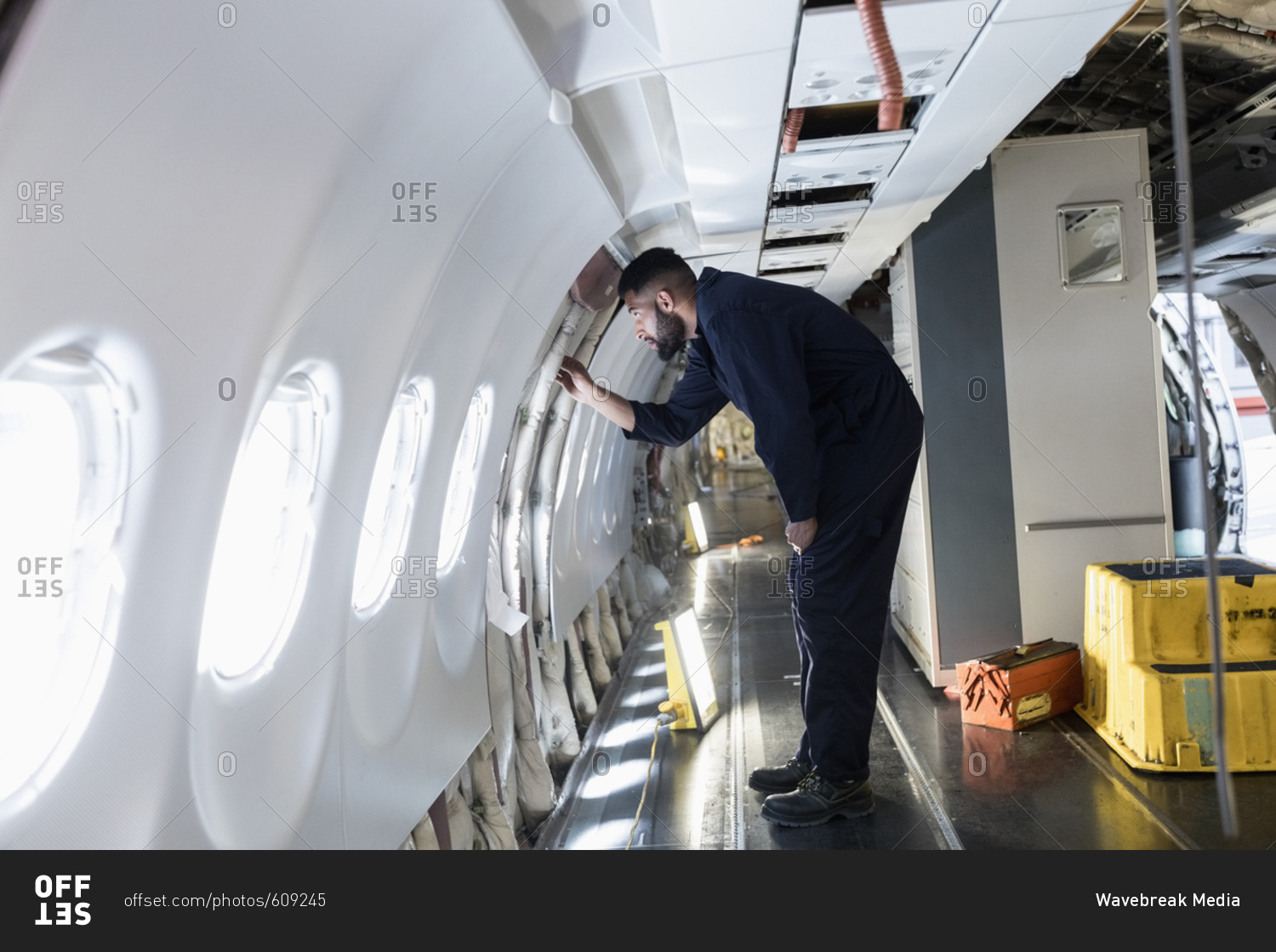 Male aircraft maintenance engineer working over internal structure of