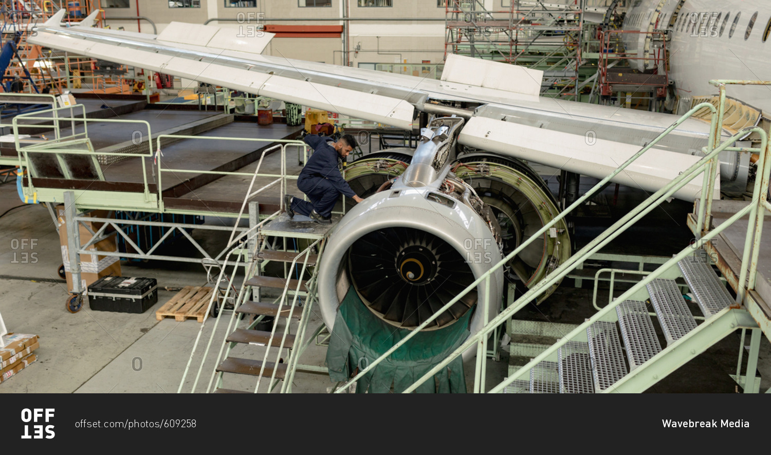 Aircraft maintenance engineer examining turbine engine of aircraft at airlines maintenance facility