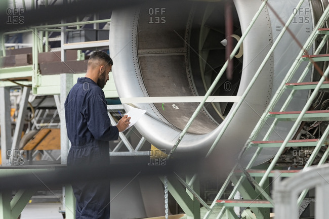 Aircraft maintenance engineer examining turbine engine of aircraft at airlines maintenance facility