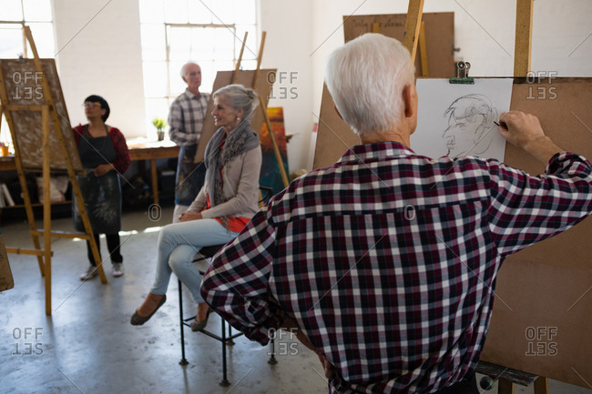 Woman sitting on chair while artists sketching on paper in art class