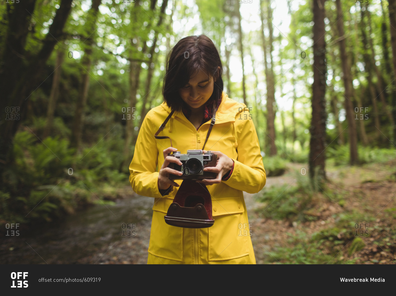 Woman looking clicked photos on vintage camera at forest