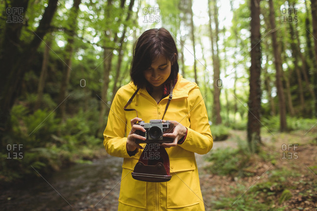 Woman looking clicked photos on vintage camera at forest