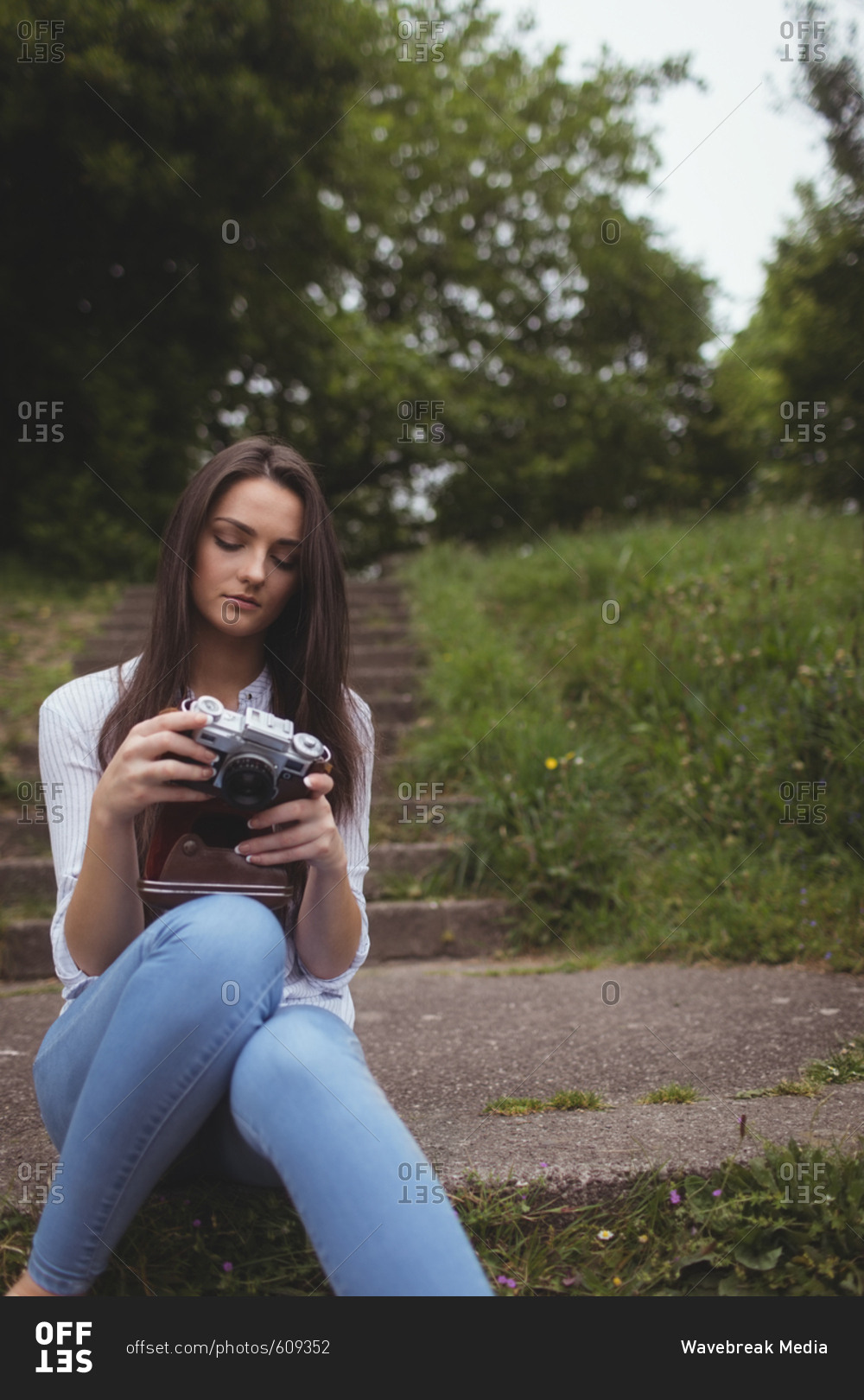Woman looking clicked photos on vintage camera at forest
