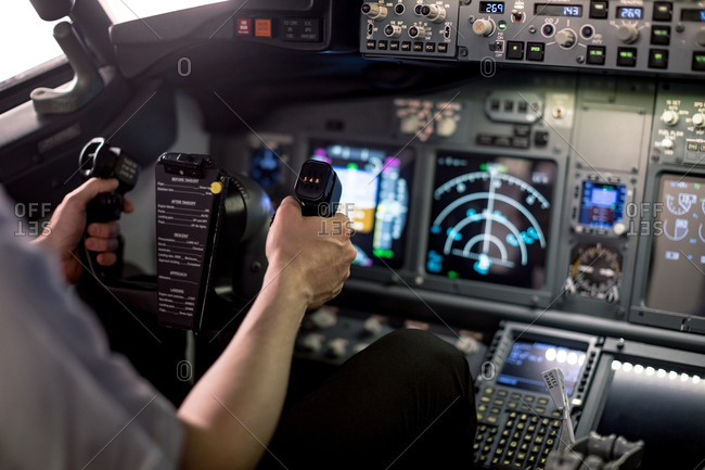 Cropped image of male pilot holding steering wheel in airplane cockpit