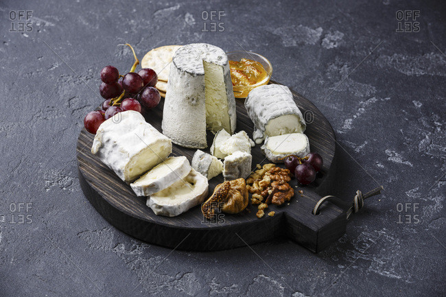 Goat Cheese board Snack assortment with confiture and grape on cutting board on black background