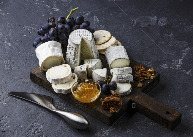 Goat Cheese board Snack assortment with confiture and grape on cutting board on black background