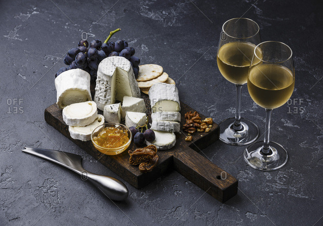 Goat Cheese board Snack assortment with confiture and grape on cutting board and wine on black background