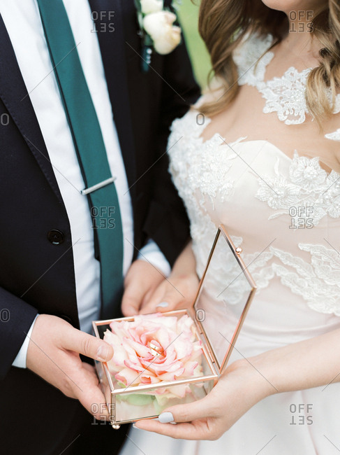 Couple holding glass box with flower and wedding bands