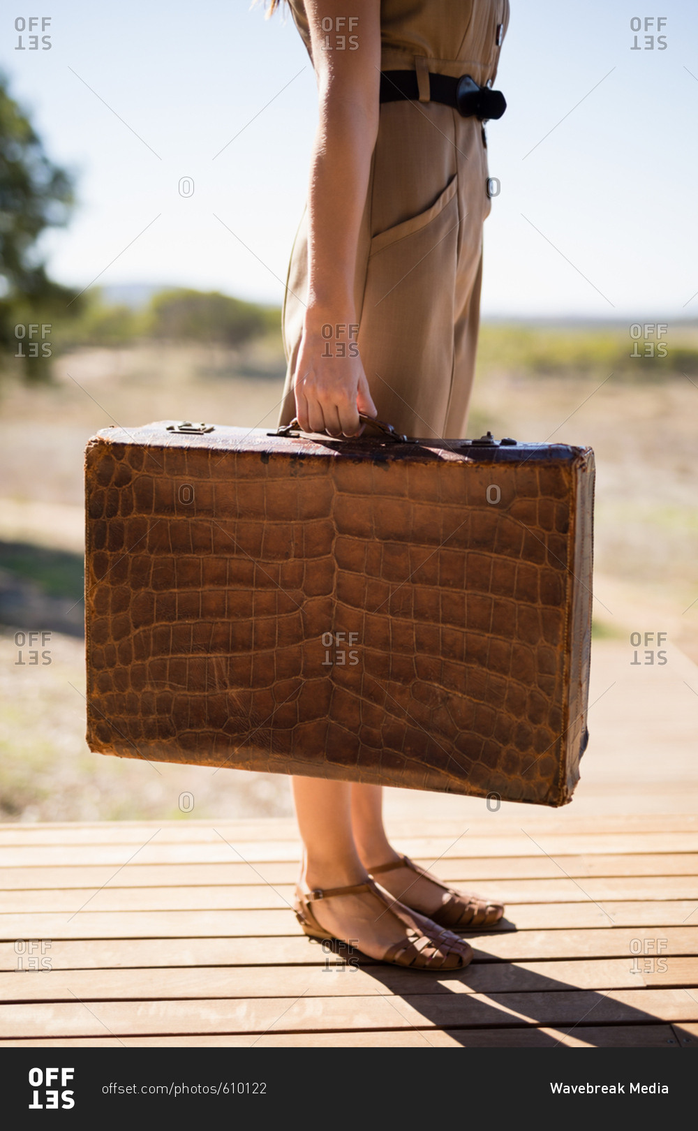 Woman with suitcase standing on deck on a sunny day during safari vacation