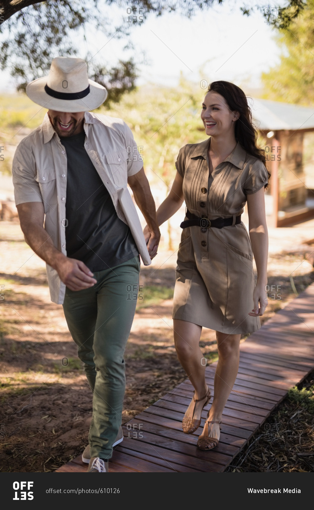 Smiling couple walking on wooden deck during safari vacation