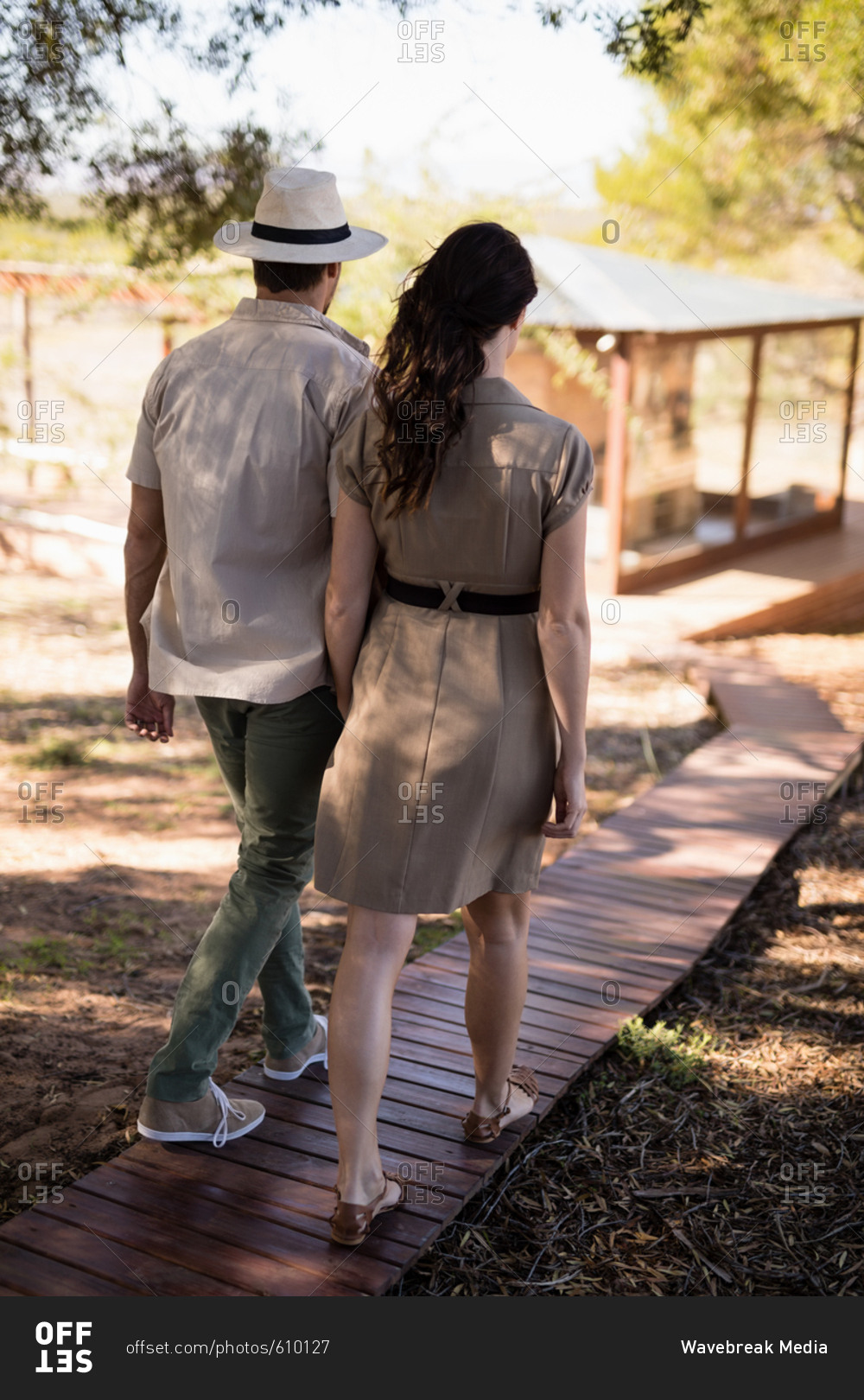 Rear view of couple walking on wooden deck during safari vacation