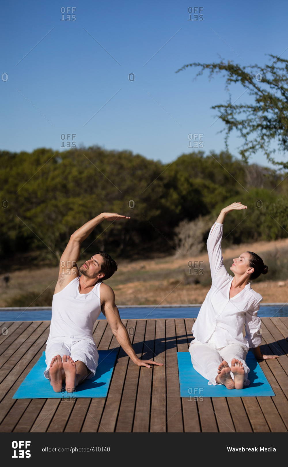 Couple performing yoga at safari vacation on a sunny day