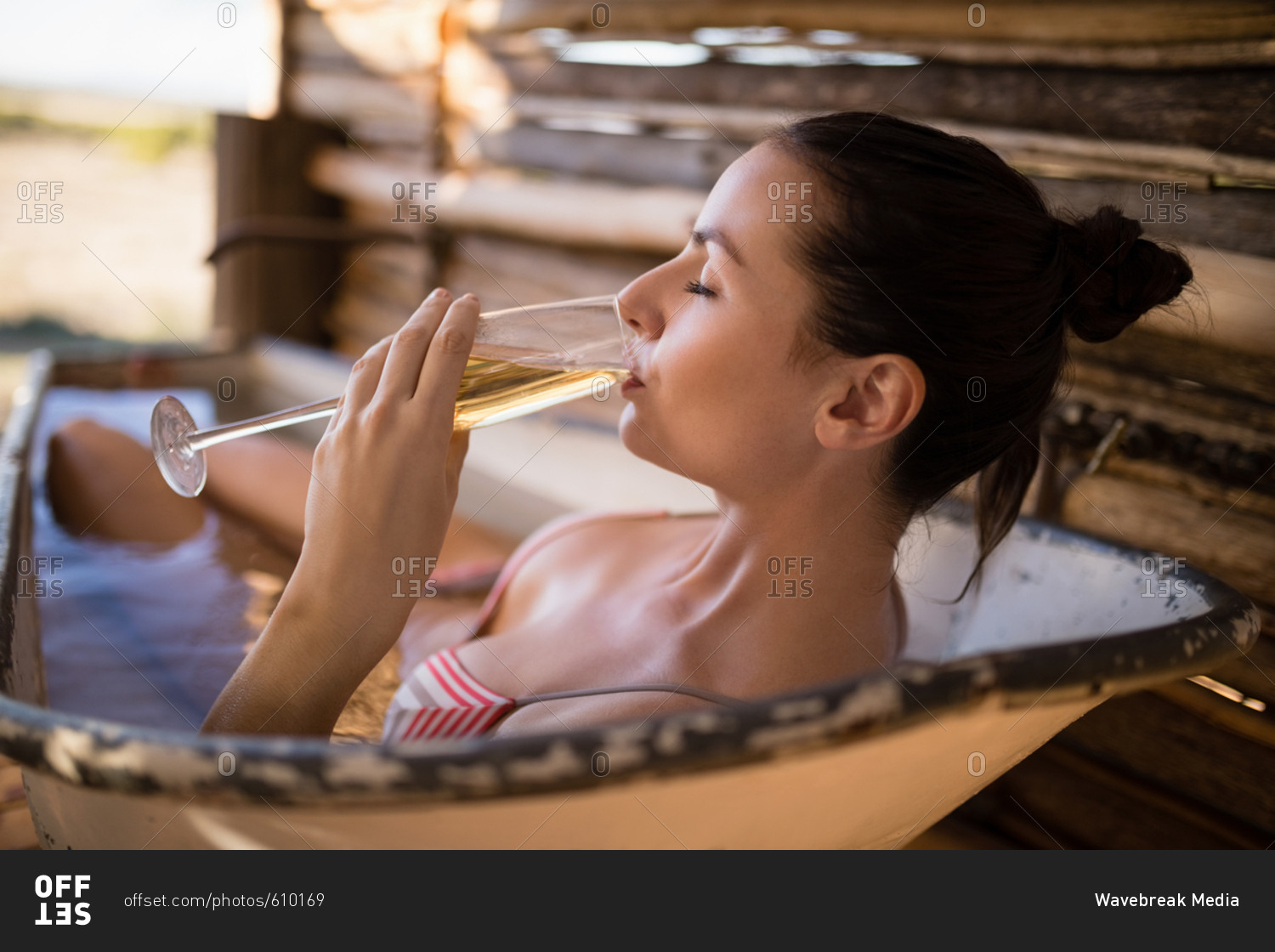 Woman having champagne in bathtub during safari vacation