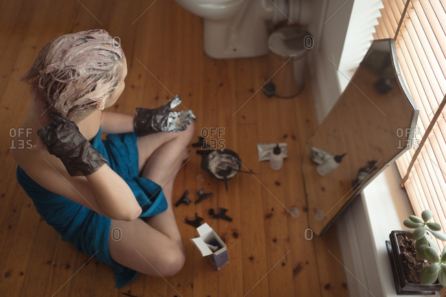 High Angle View Of Young Woman Applying Hair Dye In Bathroom At