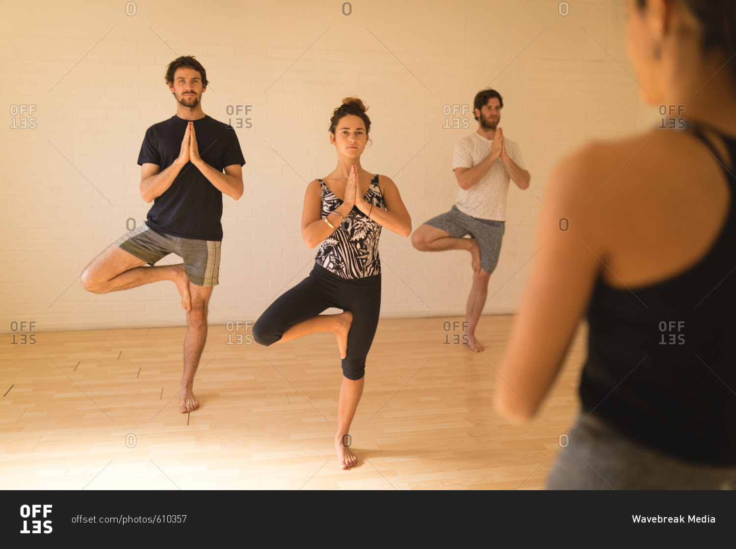 Yoga instructor guiding student in doing tree pose at yoga studio