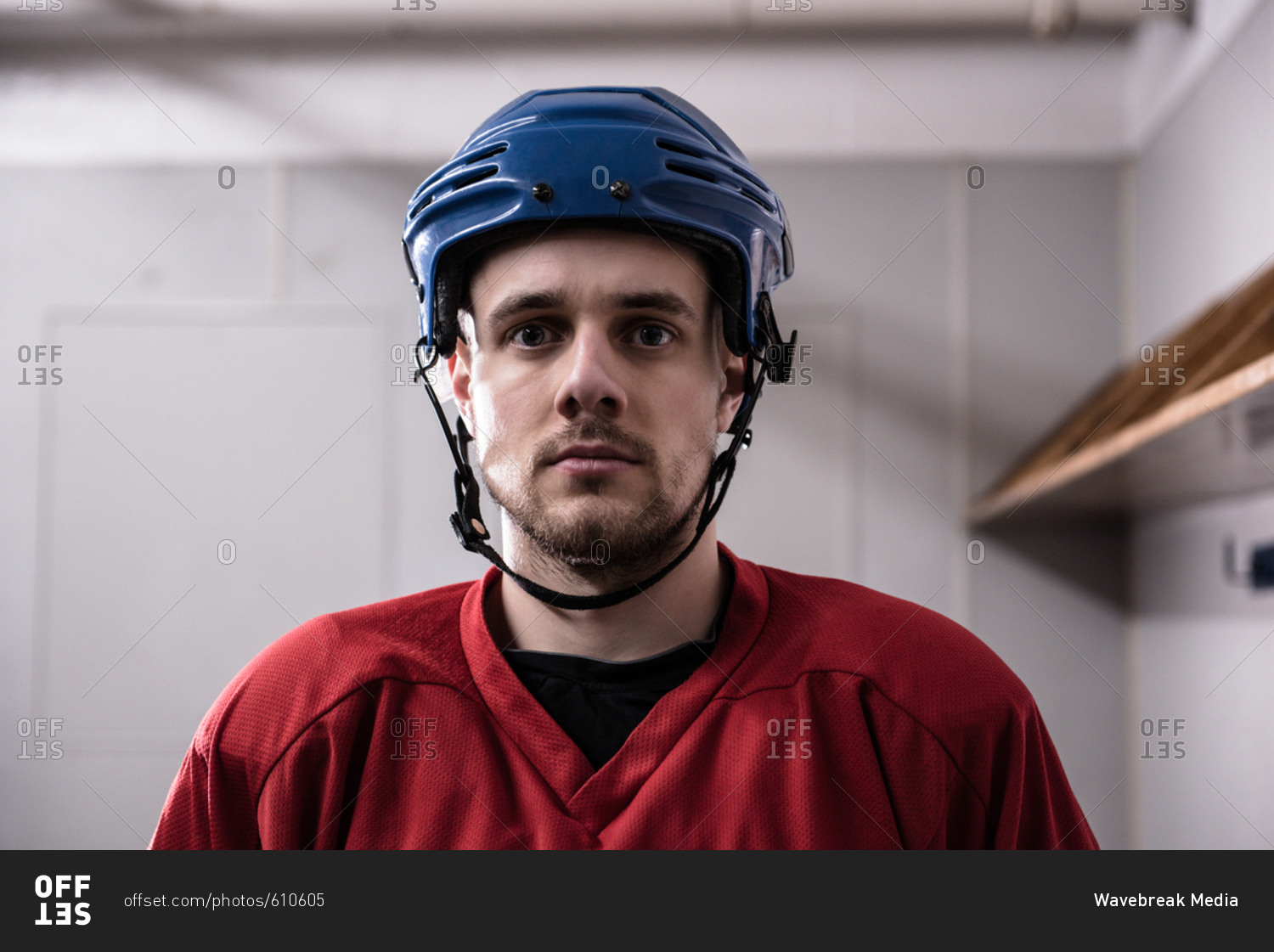 Portrait of male ice hockey player wearing helmet in dressing room ...