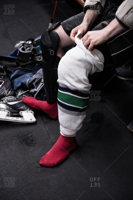 Low section of male ice hockey player wearing sock in dressing room