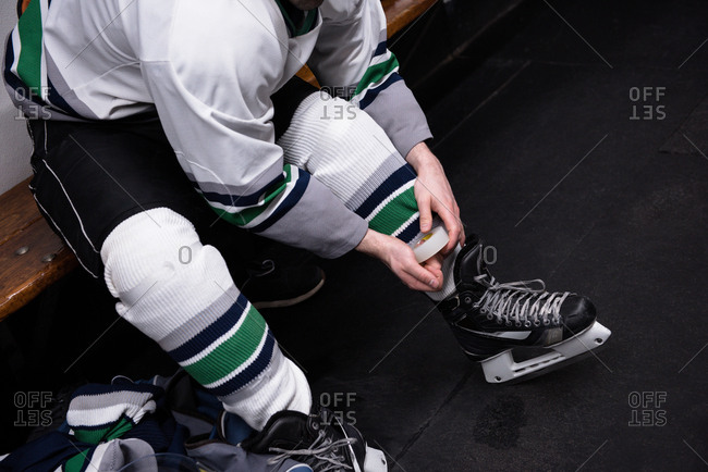 Low section of male ice hockey player wearing skate in dressing room