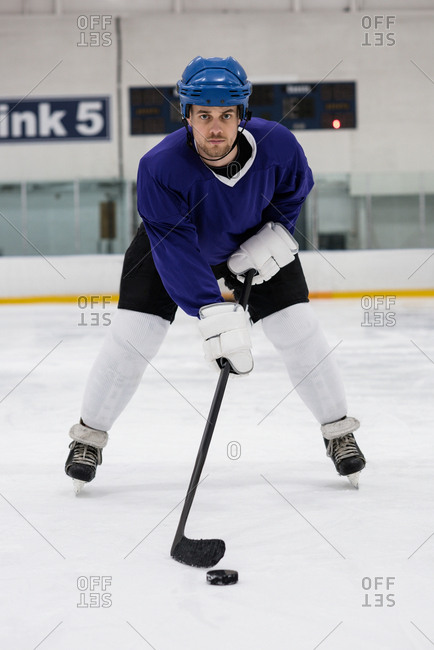 Full length portrait of player practicing ice hockey at rink