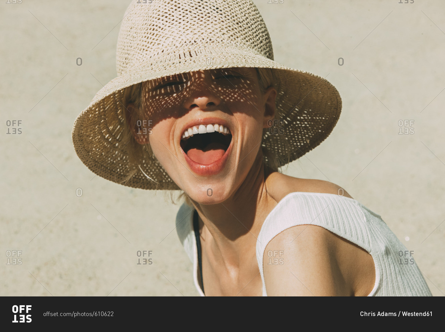 Portrait of laughing blond woman wearing summer hat